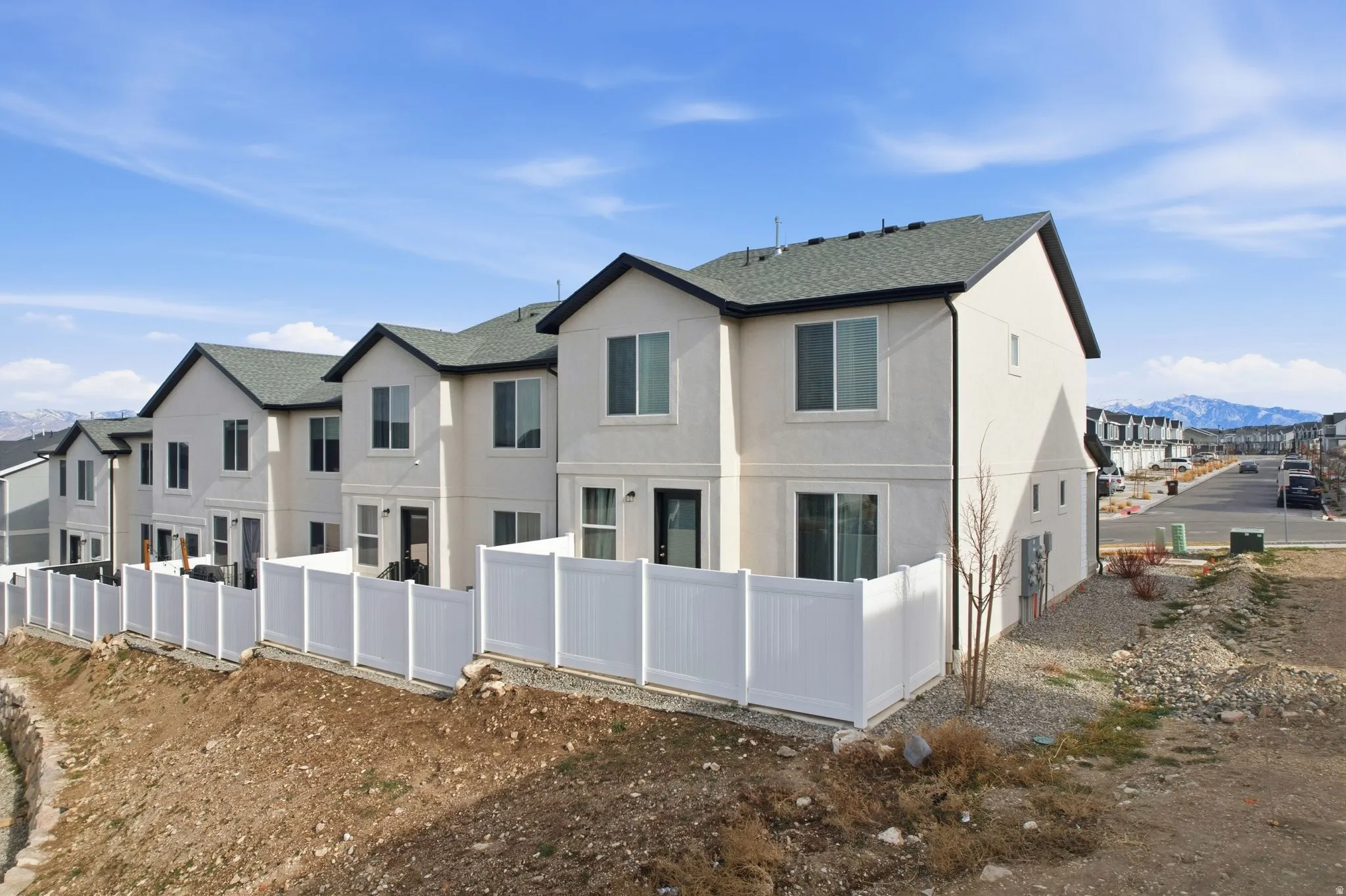 Back of property with a mountain view, stucco siding, a shingled roof, and a residential view