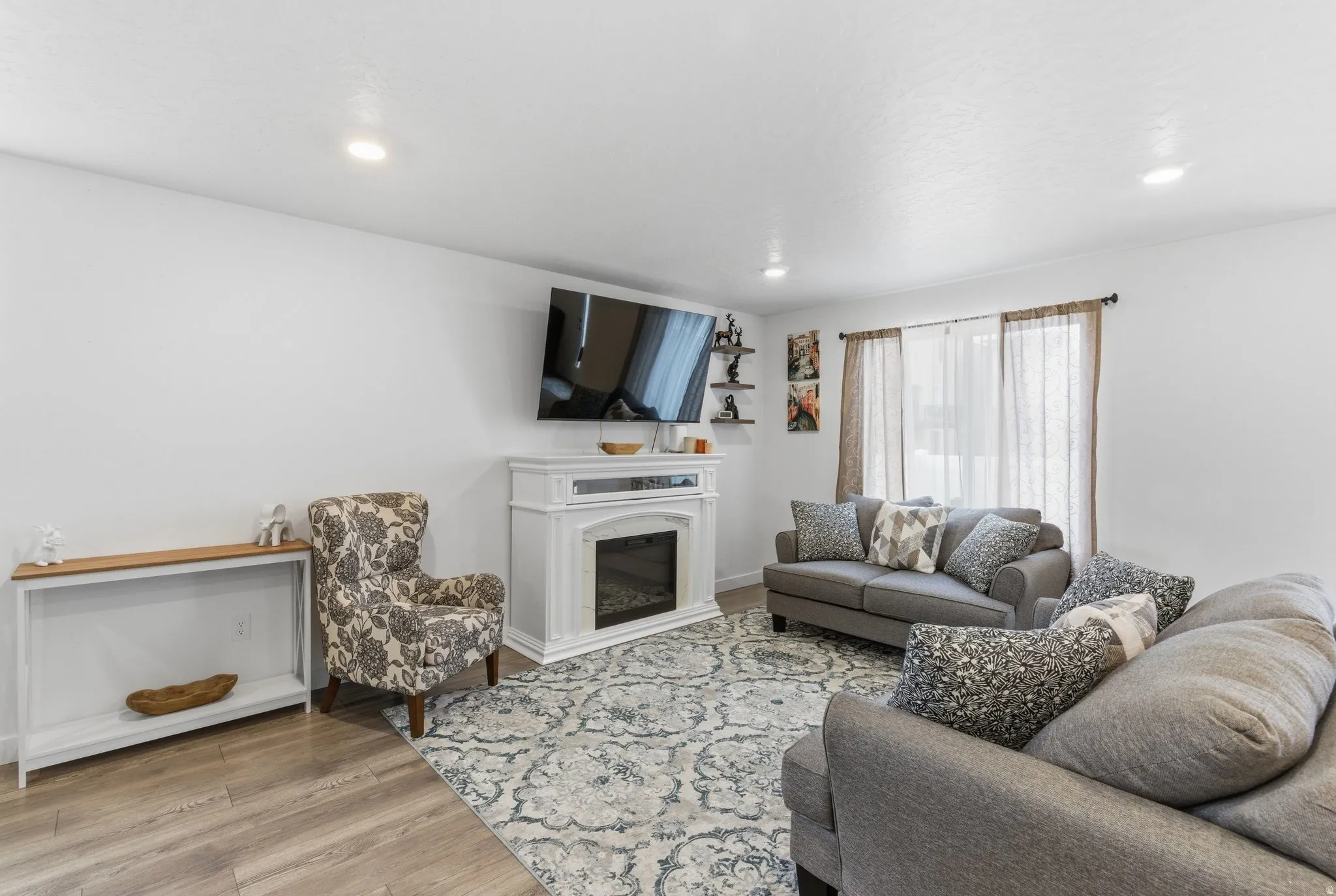 Living area with a glass covered fireplace, light wood-style floors, and recessed lighting