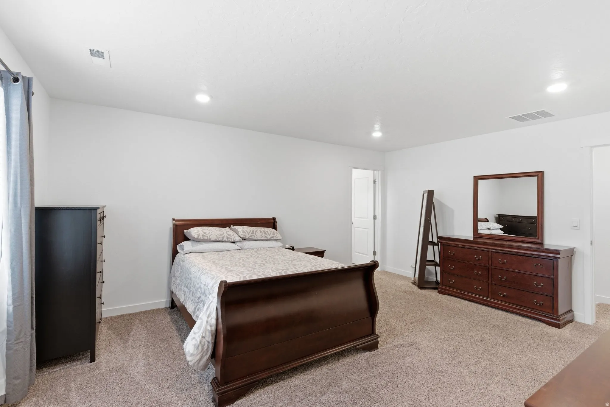 Bedroom with light colored carpet and recessed lighting