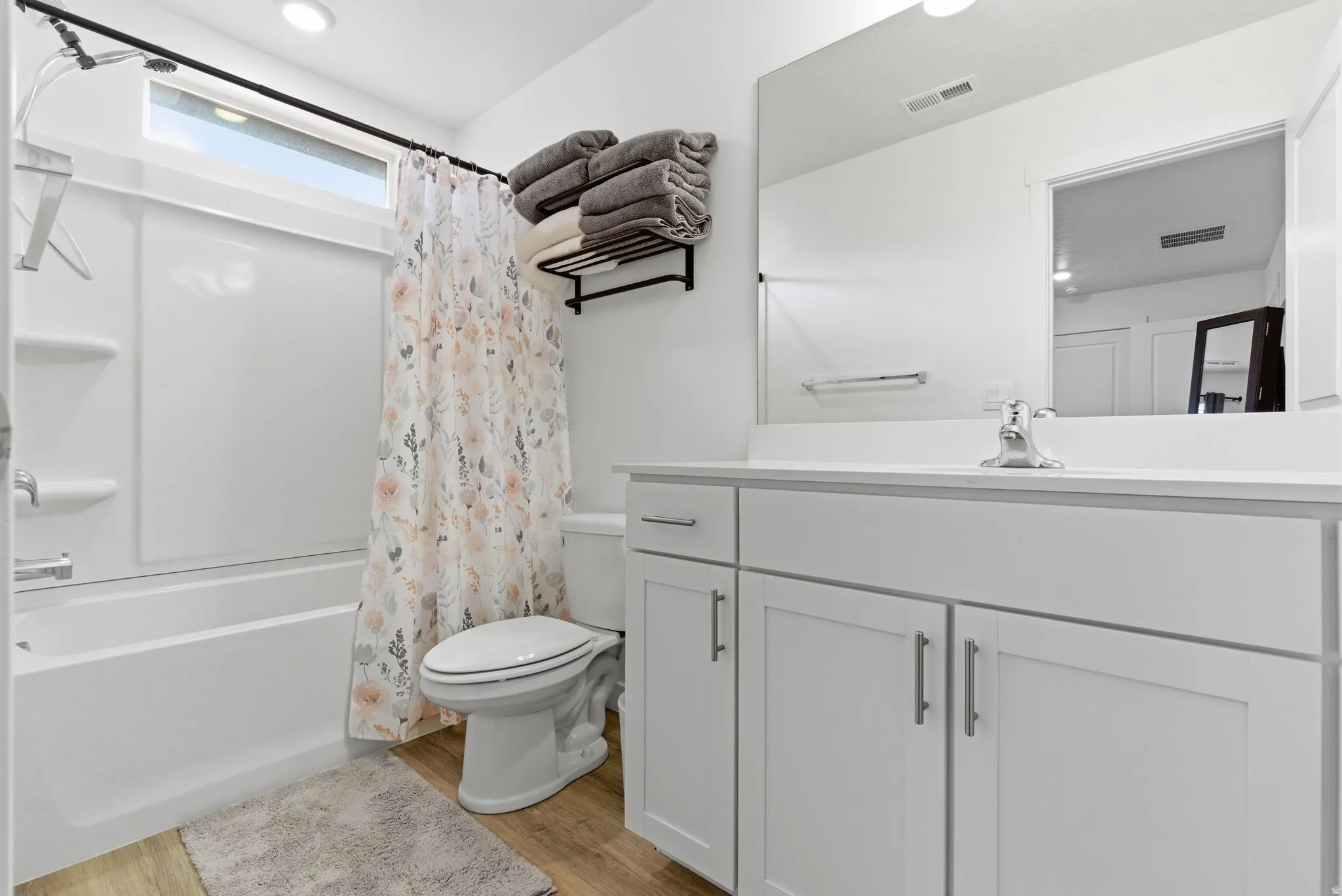 Bathroom featuring vanity, light wood finished floors, and shower / bathtub combination with curtain