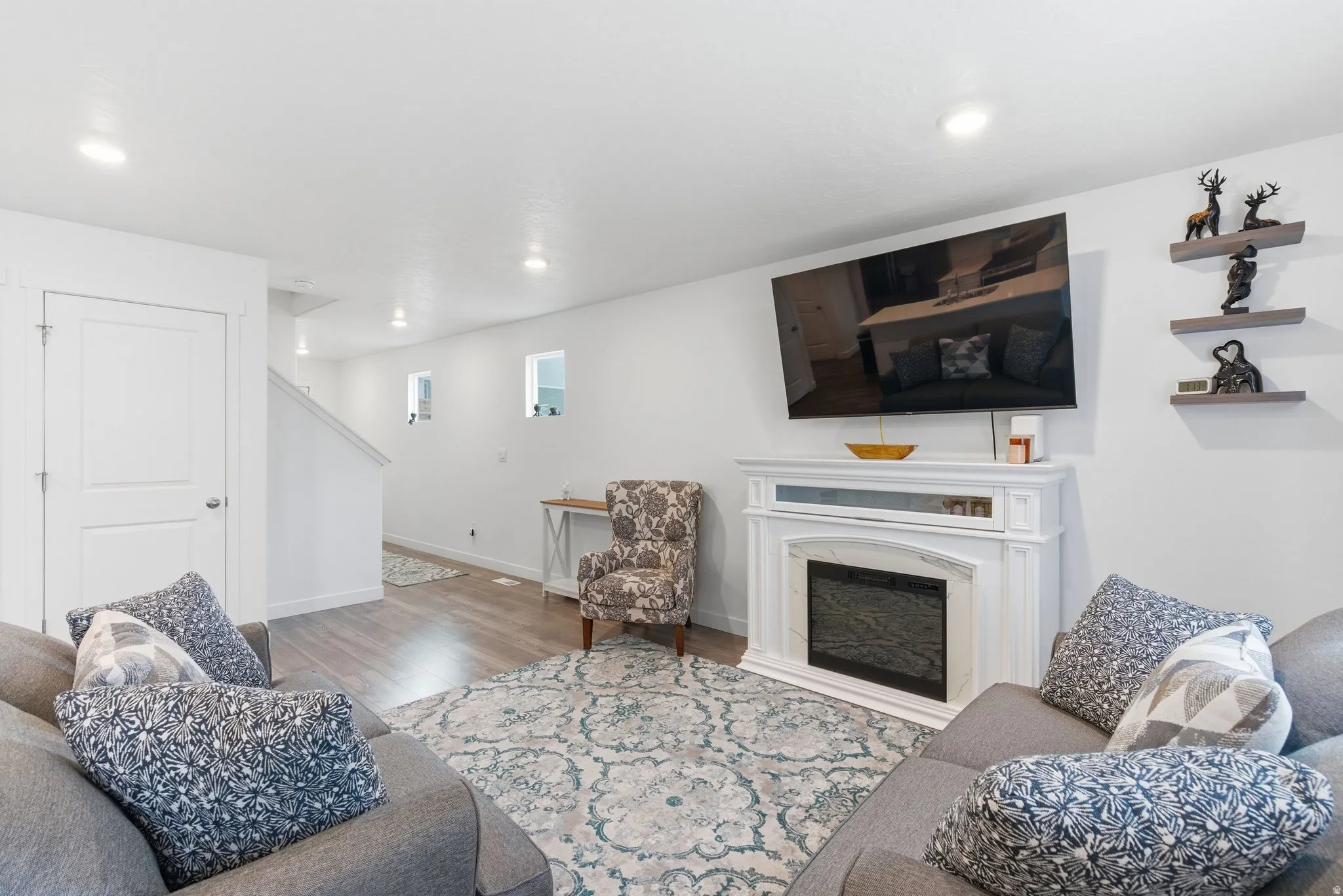 Living room with wood finished floors, a high end fireplace, and recessed lighting