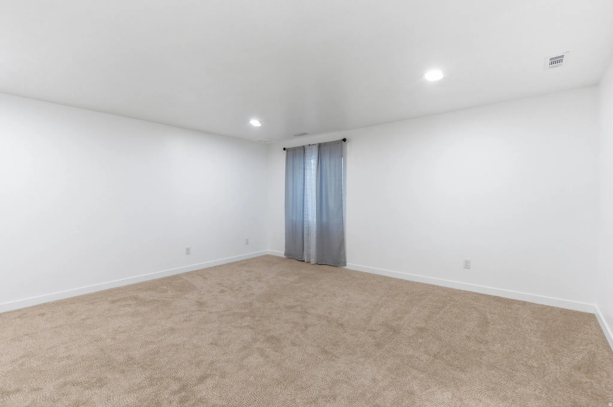 Carpeted empty room featuring recessed lighting