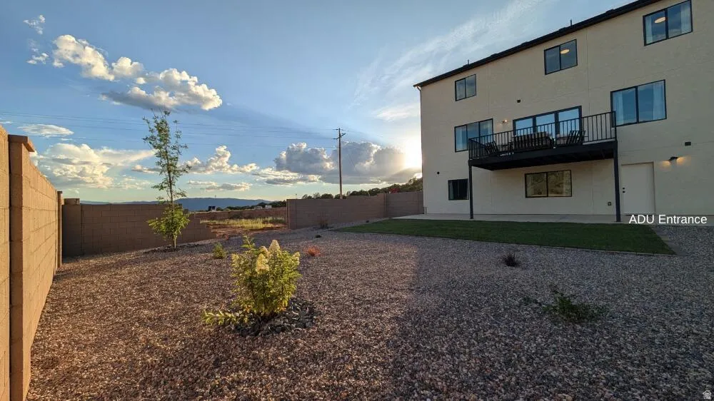 Rear exterior featuring an upper-level balcony, ground-level patio, and a dedicated entrance