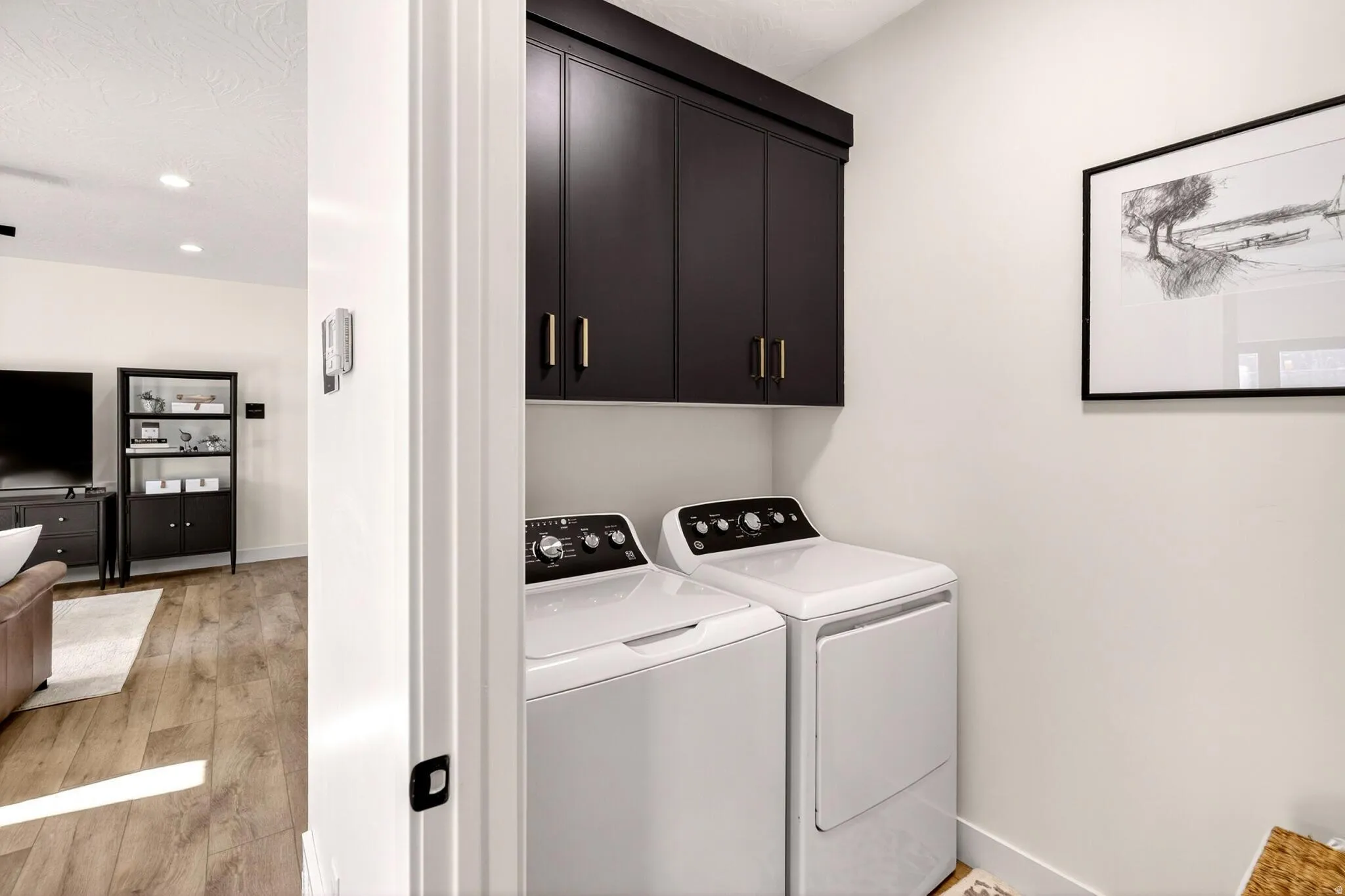 Laundry area with light wood finished floors, cabinet space, independent washer and dryer, and recessed lighting