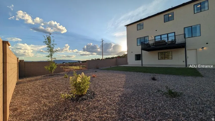 Rear exterior featuring an upper-level balcony, ground-level patio, and a dedicated entrance