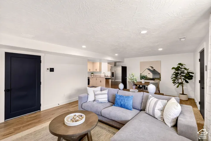 ADU Living room with light wood-type flooring, recessed lighting, and a textured ceiling.