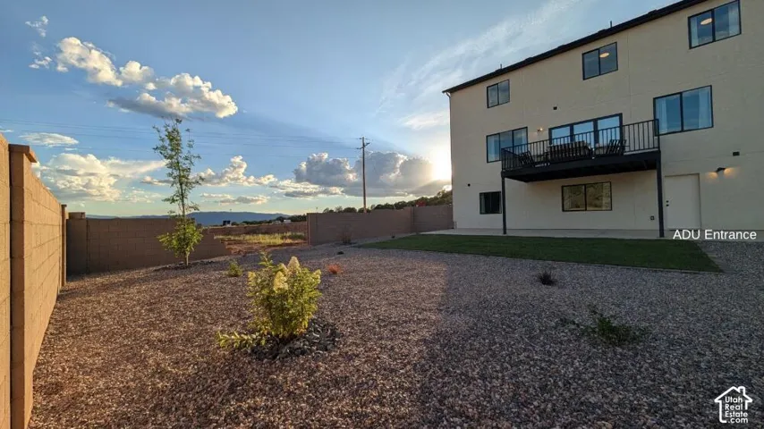 Rear exterior featuring an upper-level balcony, ground-level patio, and a dedicated entrance