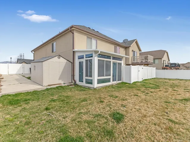 Rear view of house with a sunroom, a fenced backyard, a gate, and stucco siding