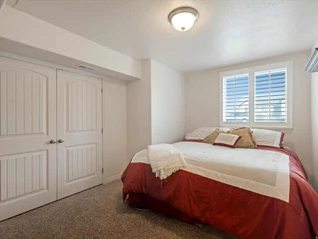 Carpeted bedroom featuring a textured ceiling and a closet