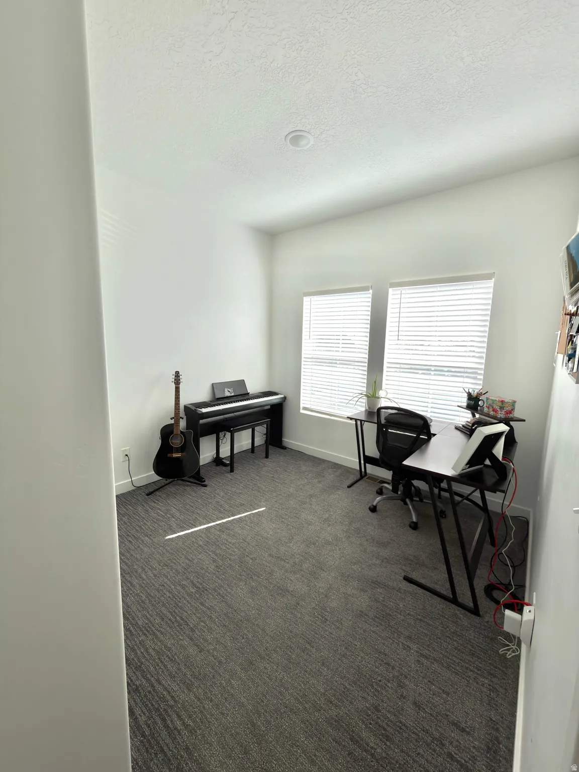 Office space featuring dark carpet and a textured ceiling