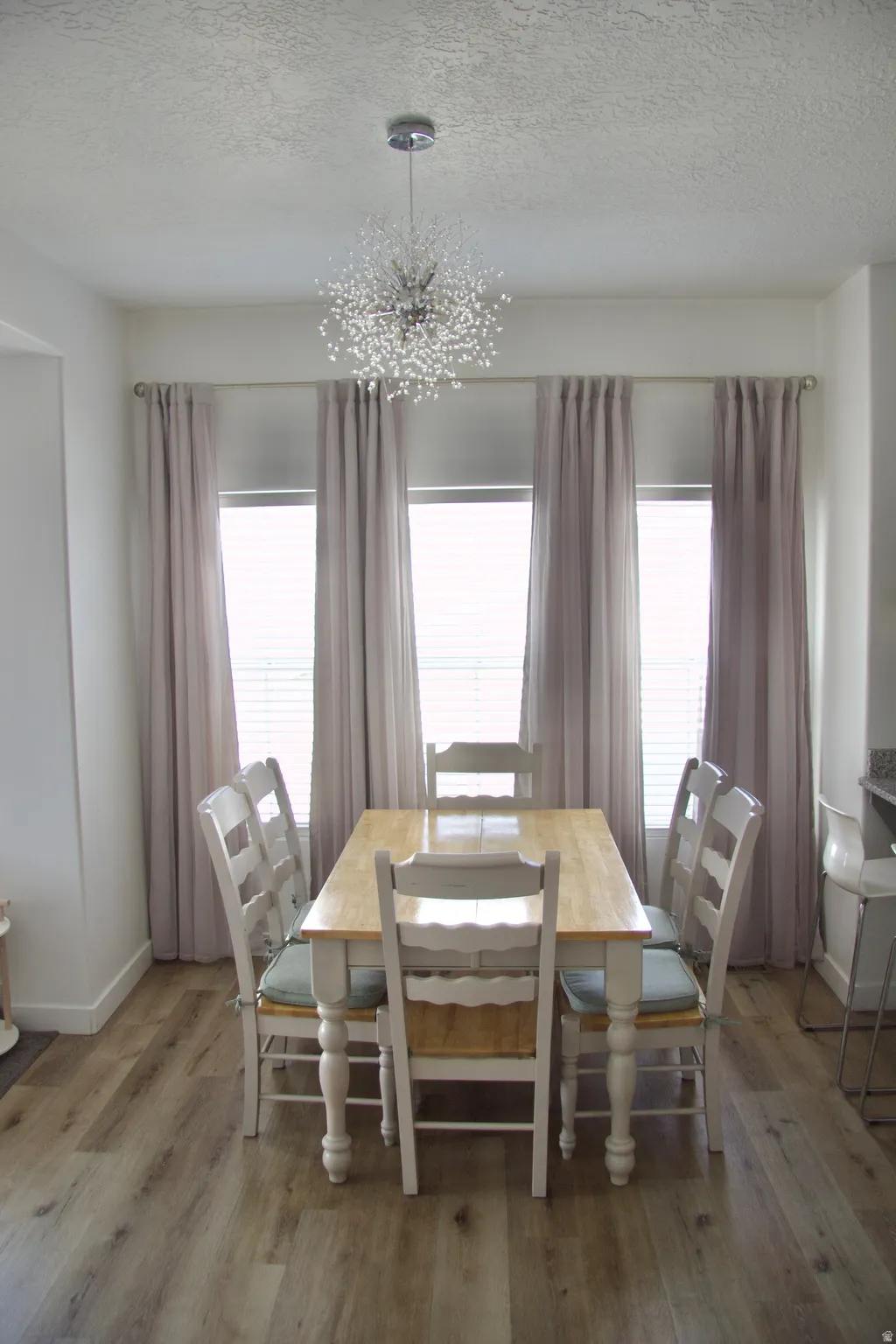 Dining area featuring a chandelier, a textured ceiling, and wood finished floors