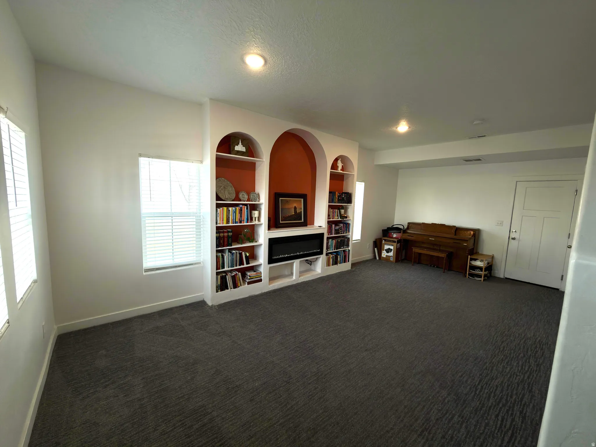 Sitting room featuring built in shelves and dark colored carpet