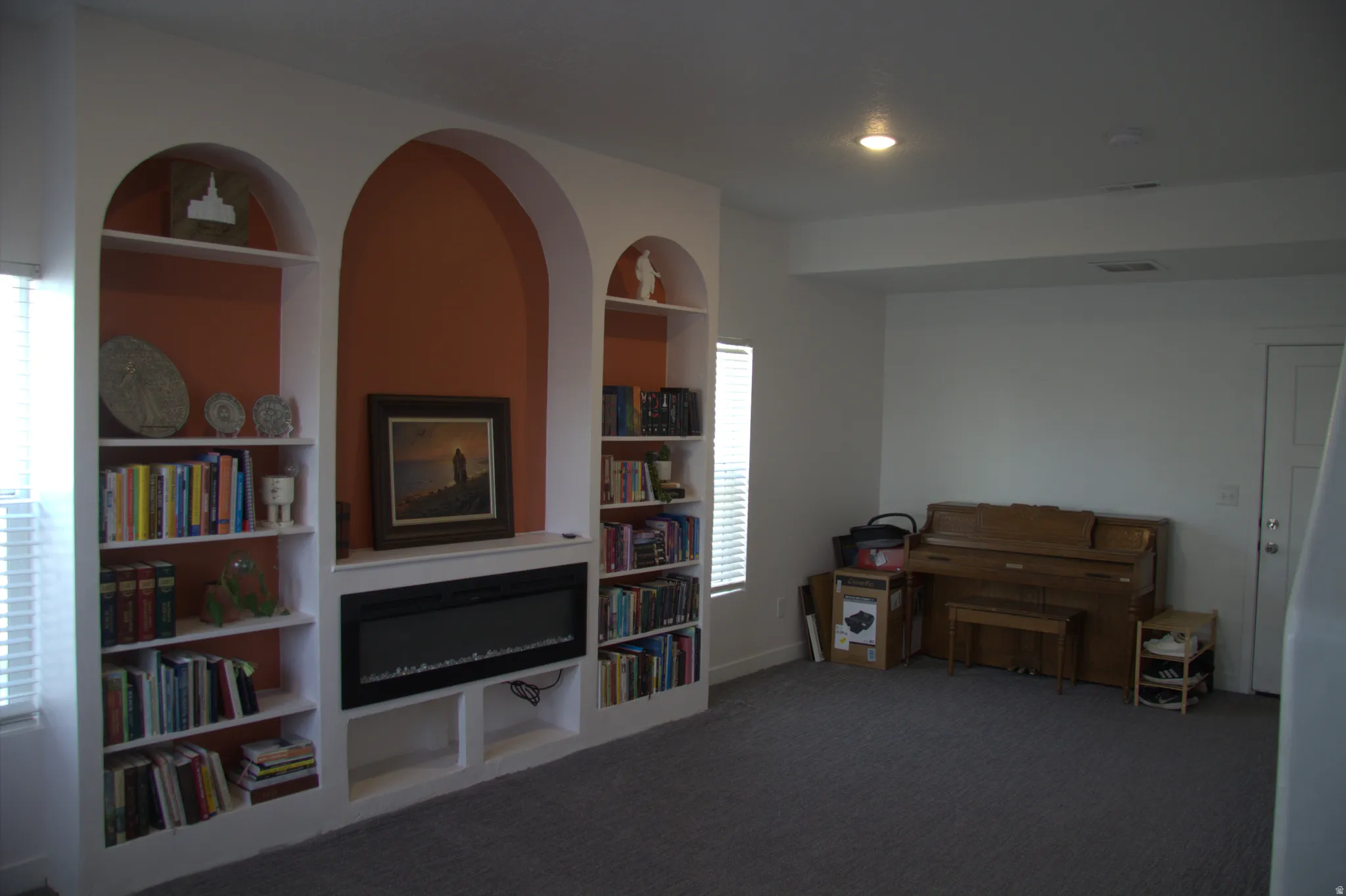 Sitting room with built in features and dark colored carpet