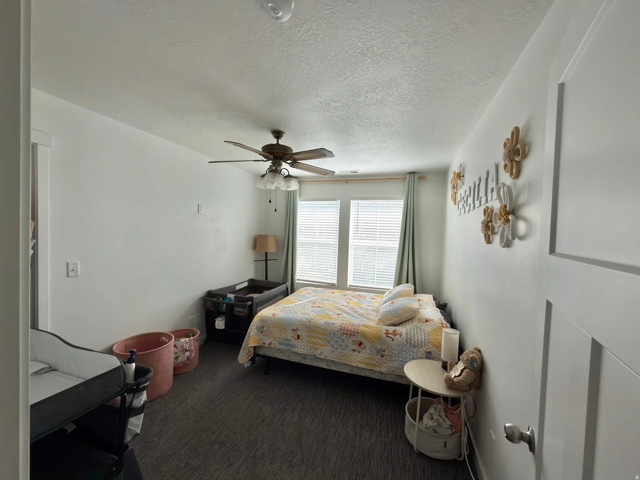 Bedroom with a textured ceiling, dark colored carpet, and ceiling fan