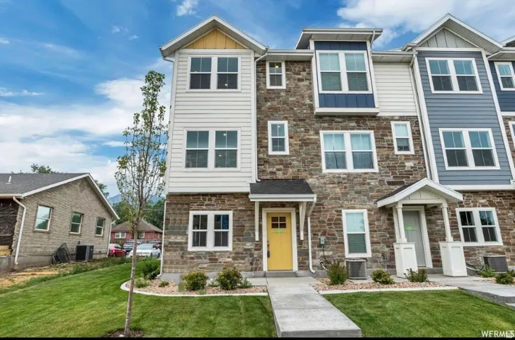 Craftsman-style home with board and batten siding, a front yard, and stone siding