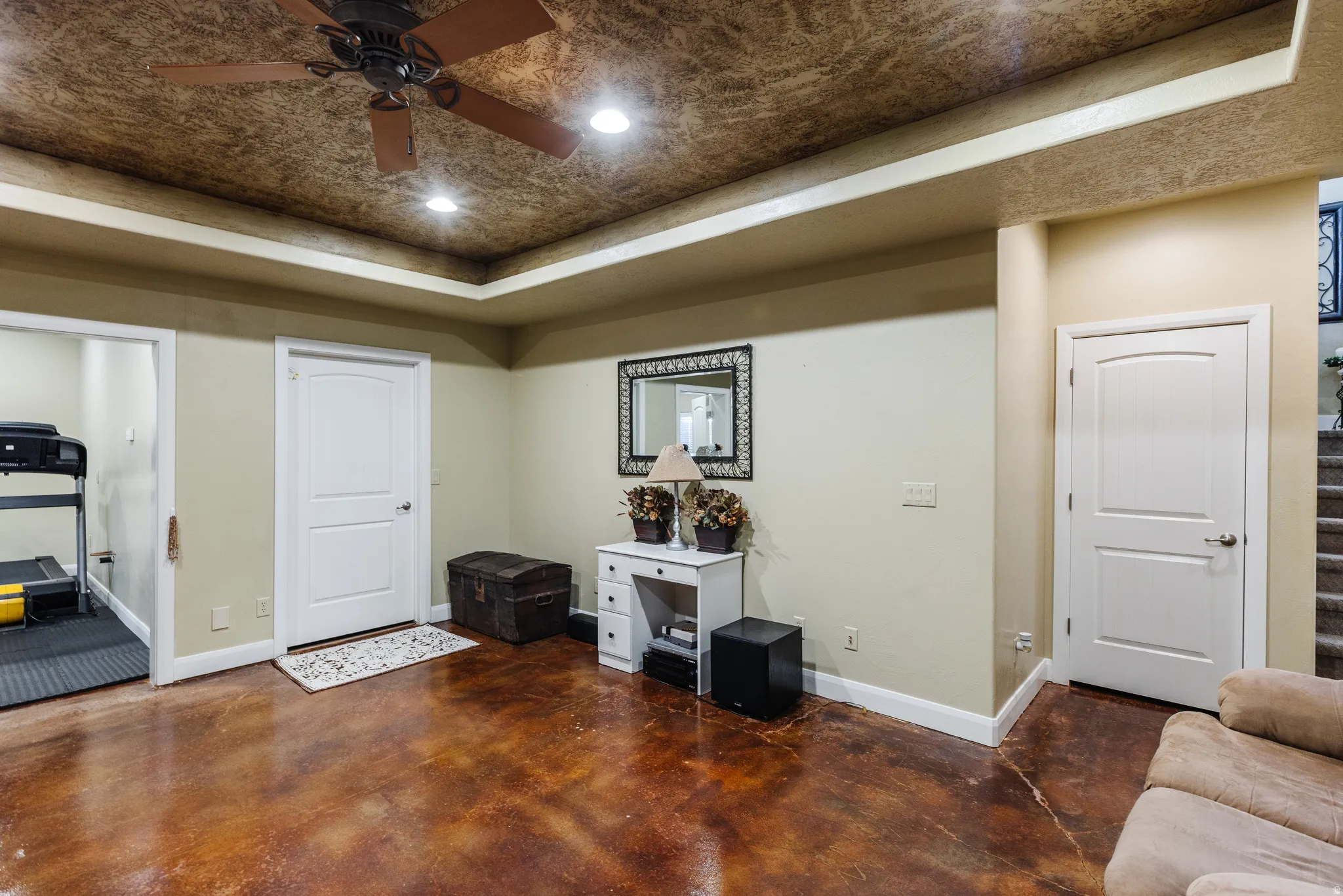 Sitting room with finished concrete floors, a tray ceiling, ceiling fan, and recessed lighting