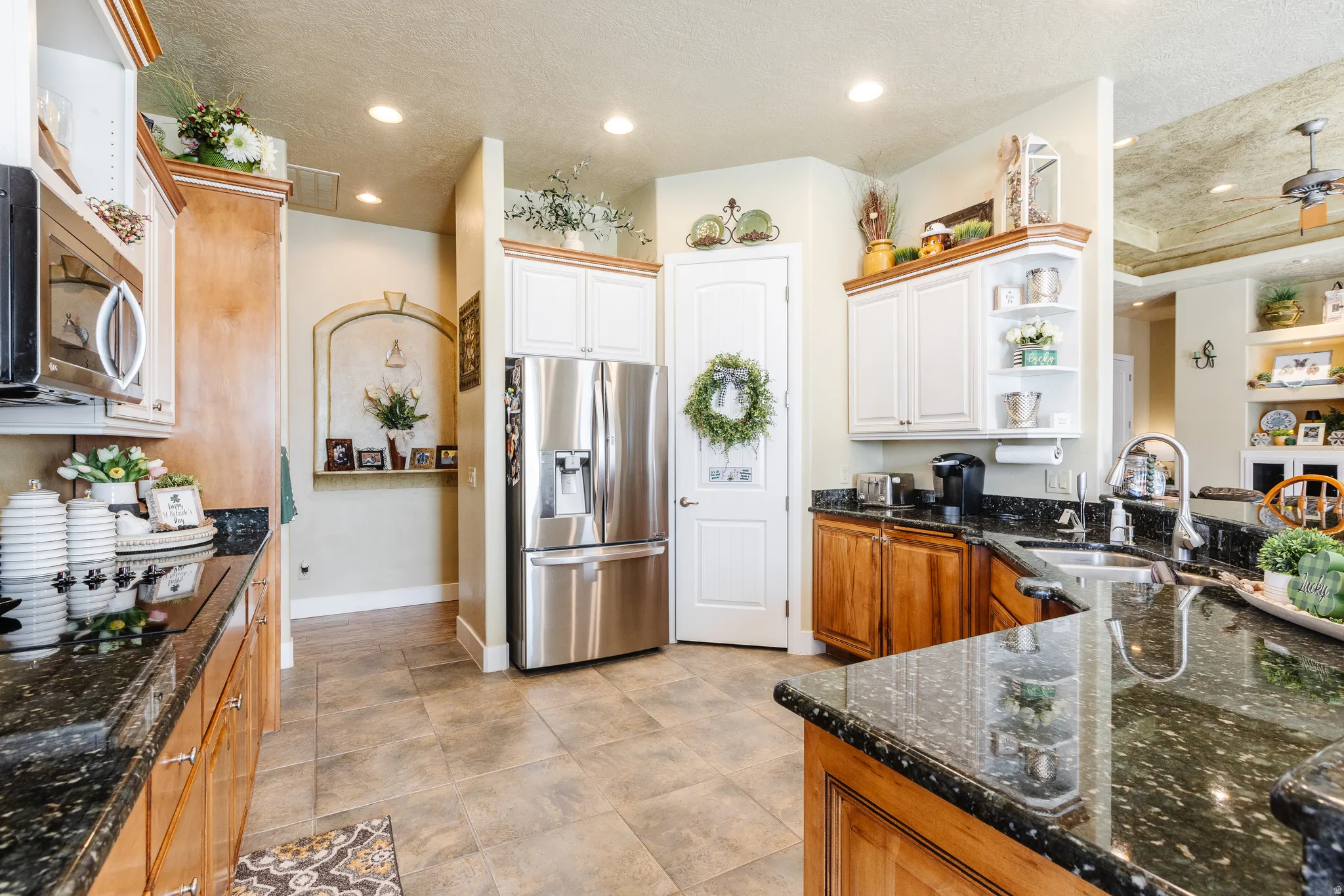 Kitchen featuring dark stone countertops, stainless steel appliances, a ceiling fan, open shelves, and a textured ceiling
