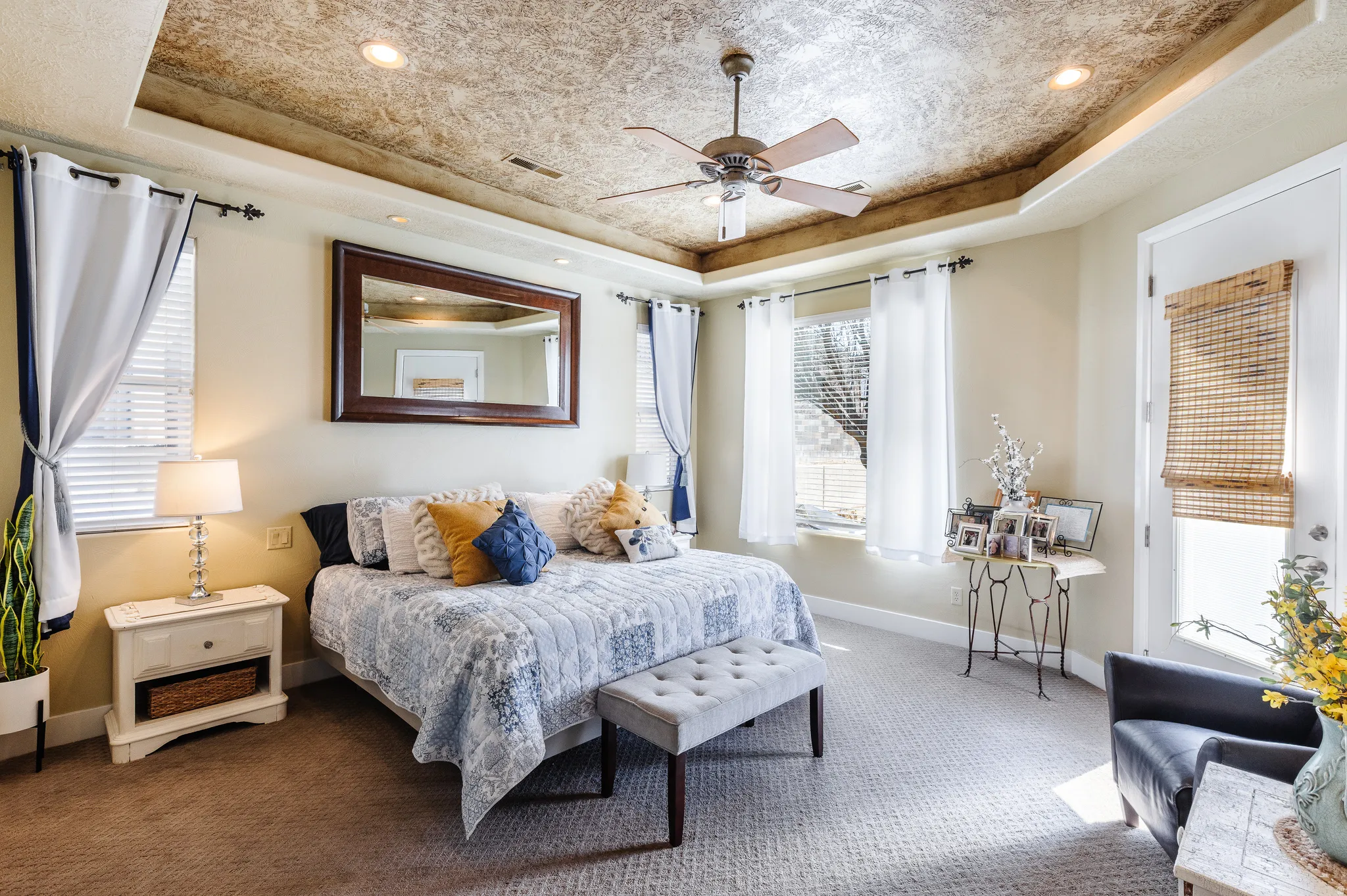 Carpeted bedroom featuring a raised ceiling, ceiling fan, and recessed lighting
