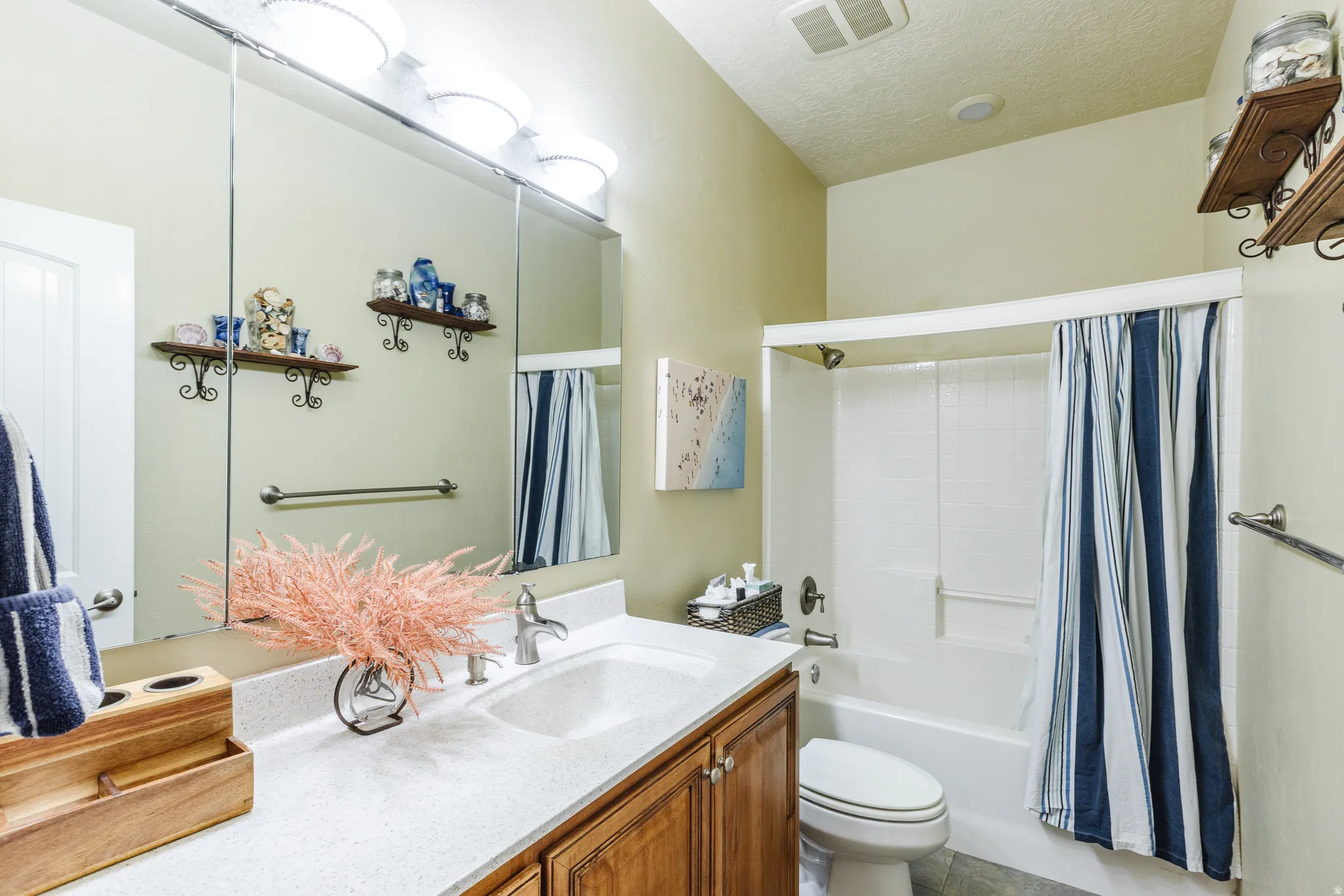 Bathroom with vanity, shower / bath combo with shower curtain, and a textured ceiling