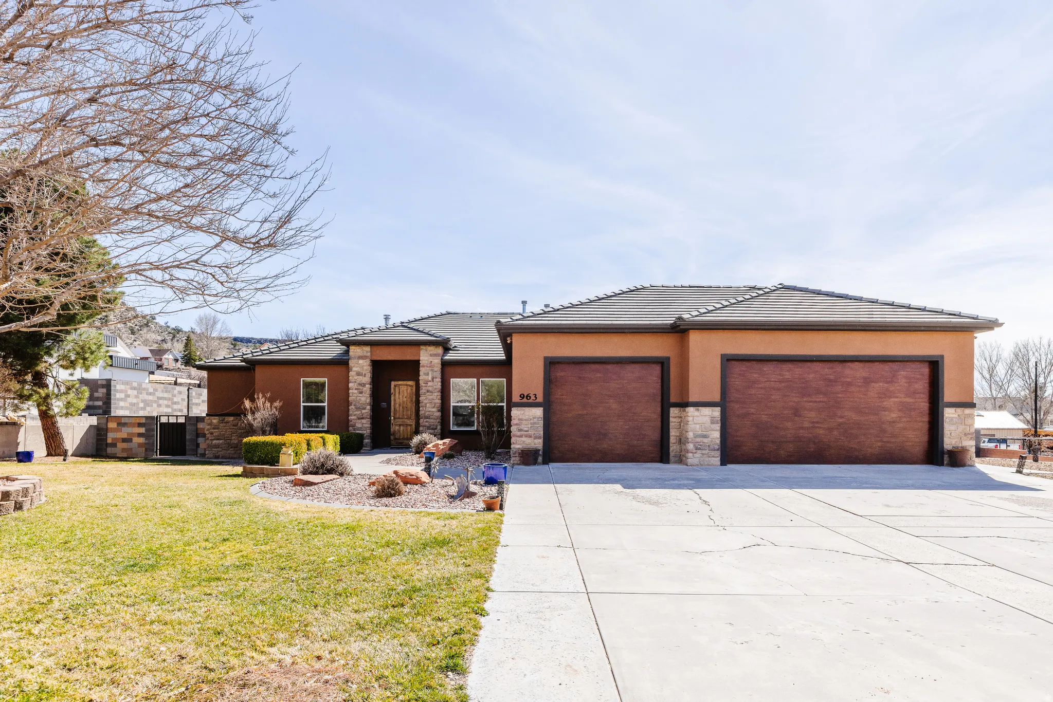 Prairie-style home featuring stone siding, a front lawn, driveway, and stucco siding