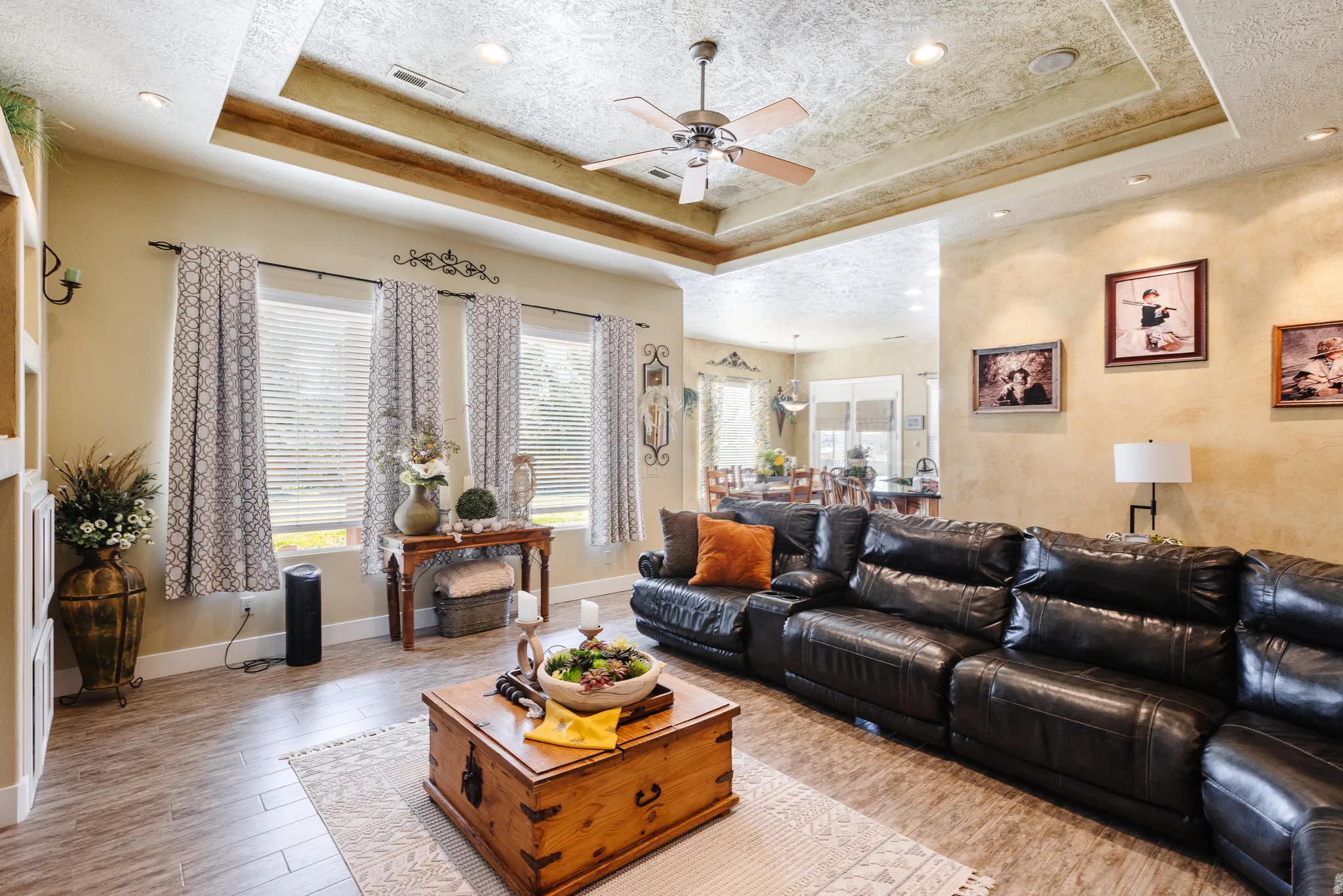 Living room with a ceiling fan, light wood-type flooring, a textured ceiling, a tray ceiling, and recessed lighting