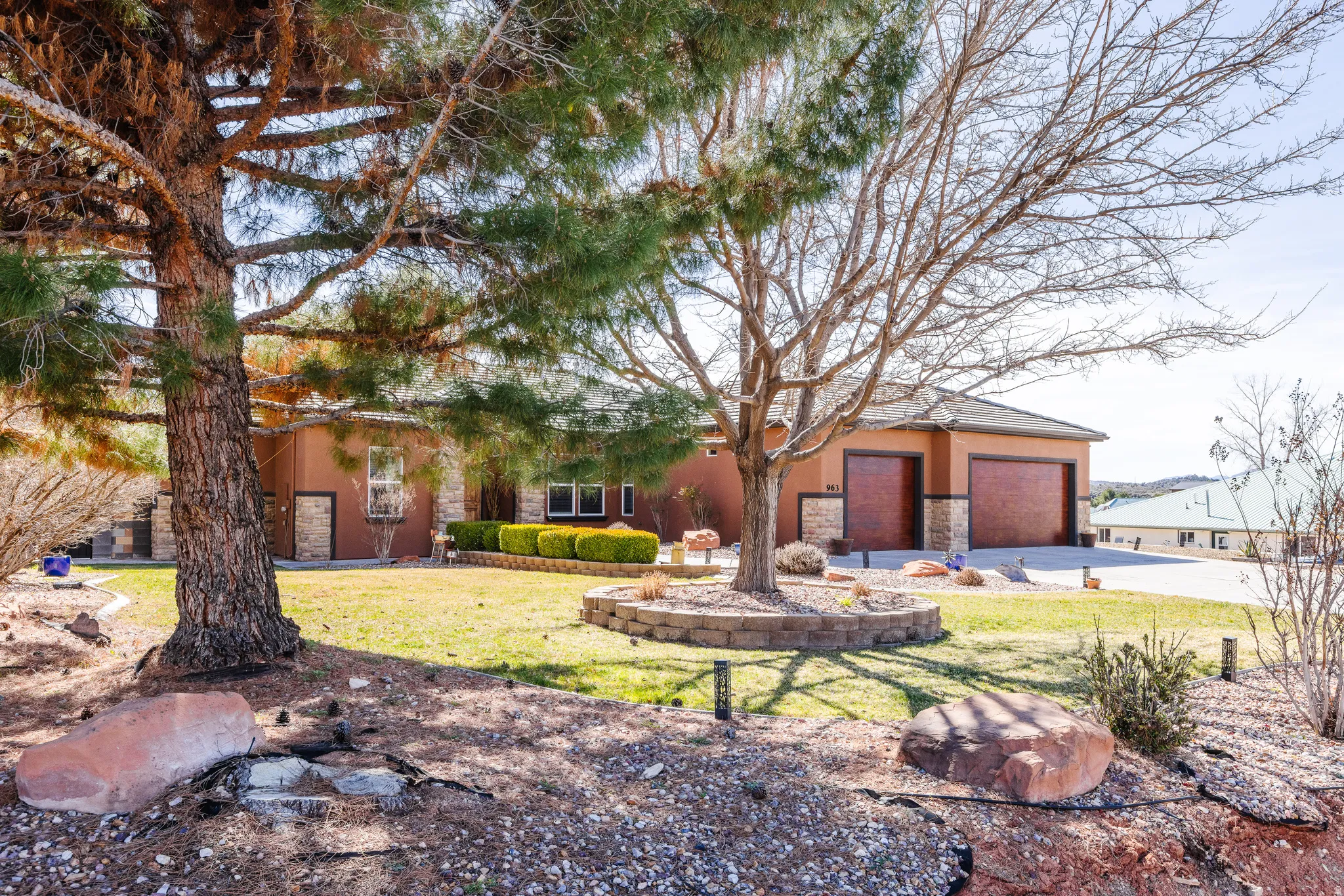 View of front of home with stone siding, stucco siding, a front lawn, and concrete driveway