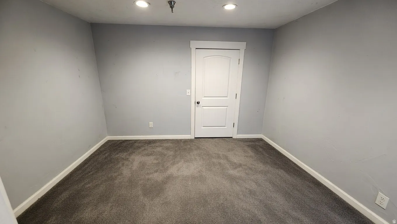 Empty room with dark colored carpet and recessed lighting