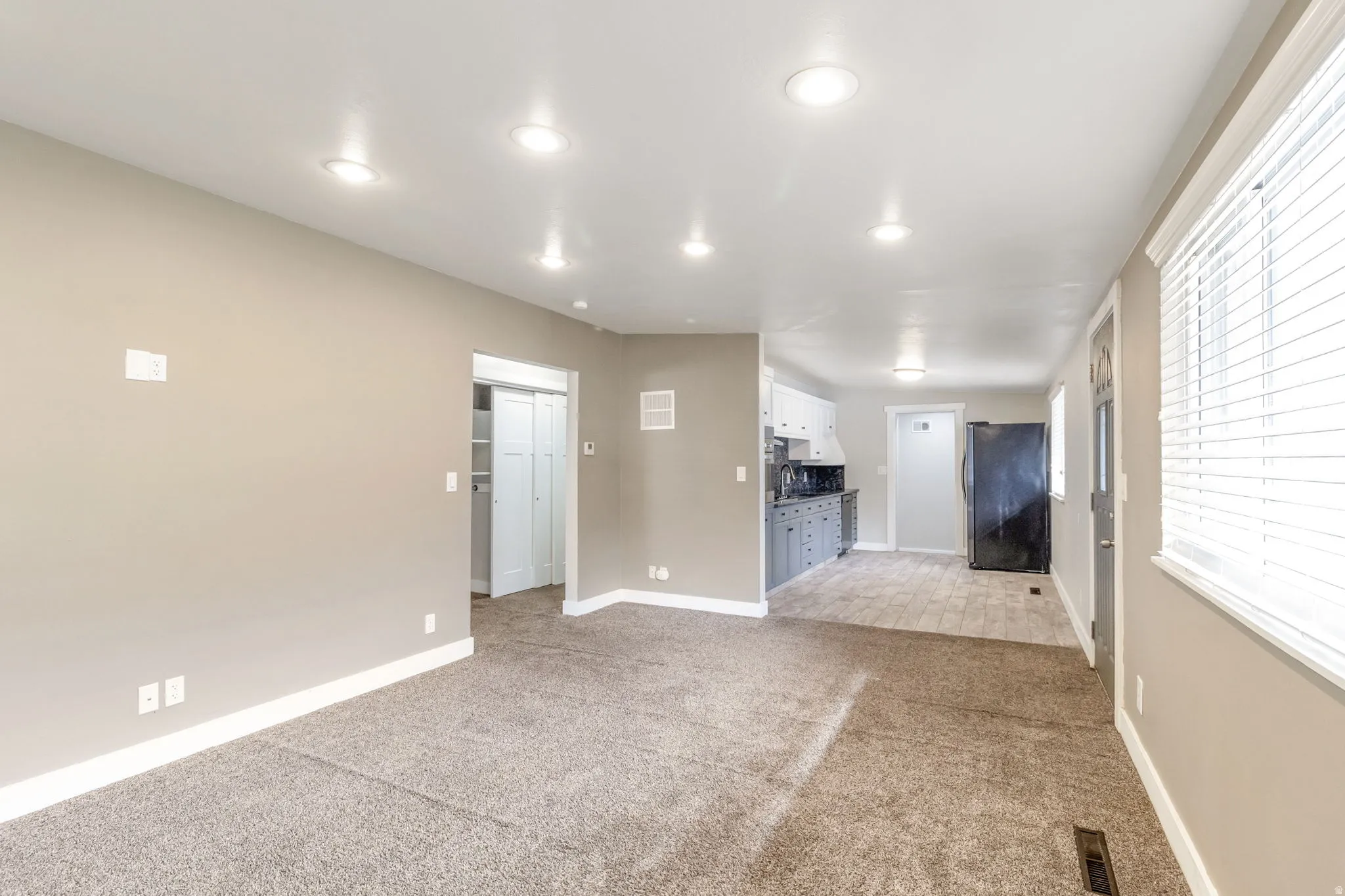 Unfurnished living room with light colored carpet and recessed lighting