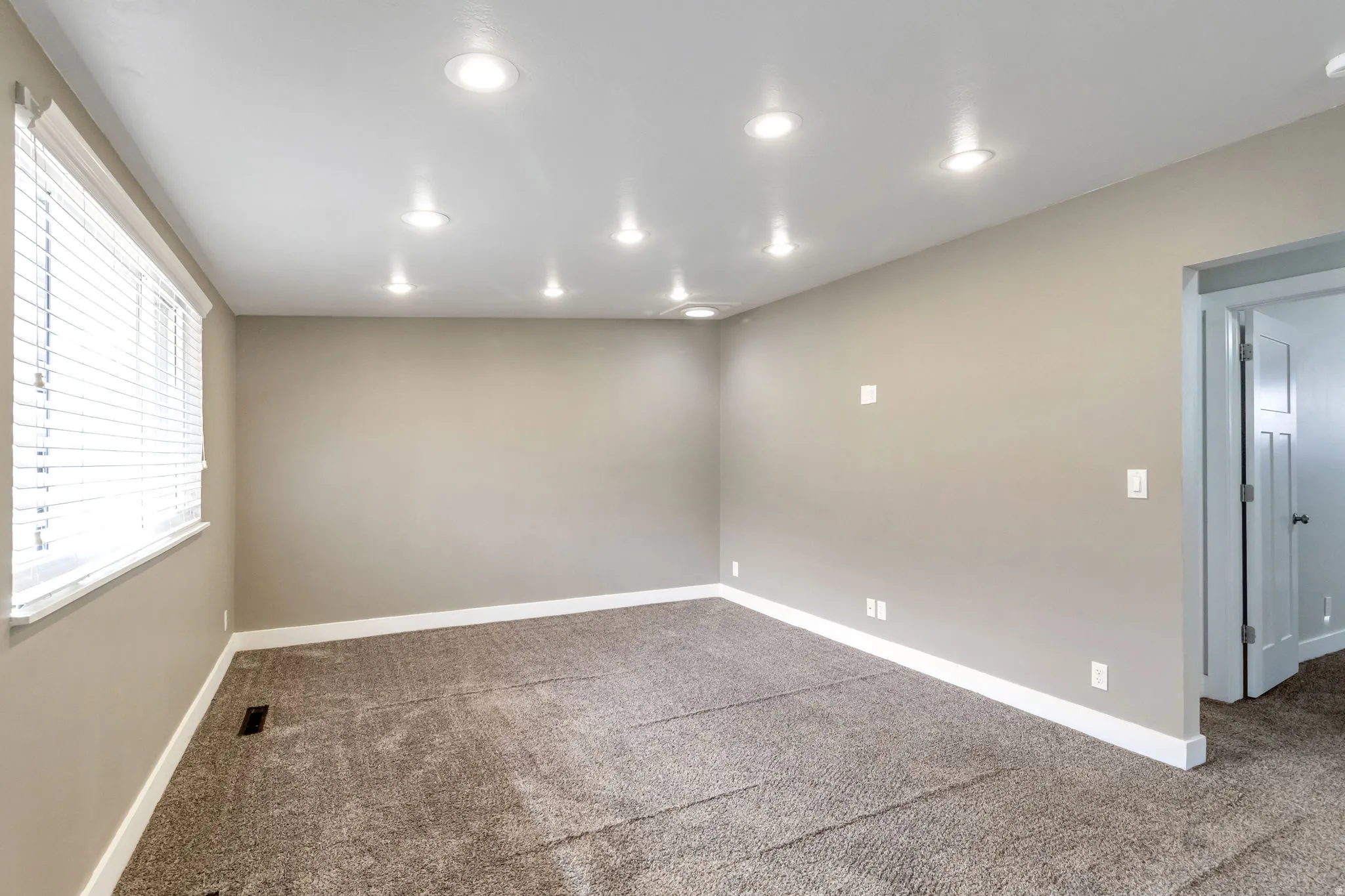 Unfurnished room with dark colored carpet and recessed lighting