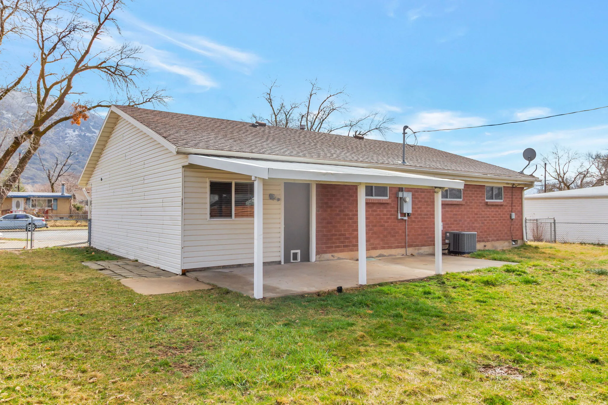 Back of house with a patio area, brick siding, a shingled roof, and a gate