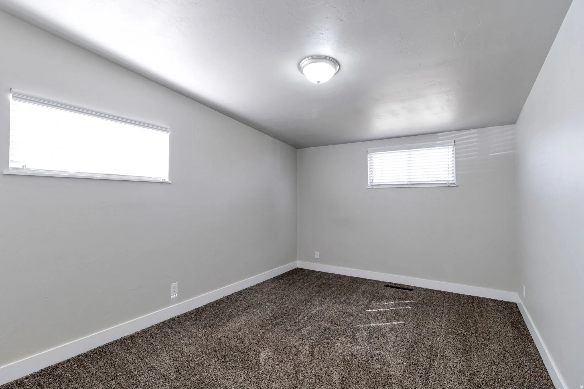 Empty bedroom room with dark carpet and lofted ceiling