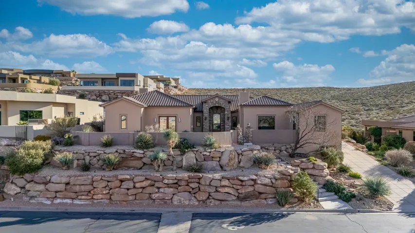 Mediterranean / spanish-style home with stucco siding, stone siding, and a chimney