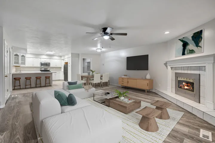 Living area featuring light wood-type flooring, a ceiling fan, a tiled fireplace, and recessed lighting