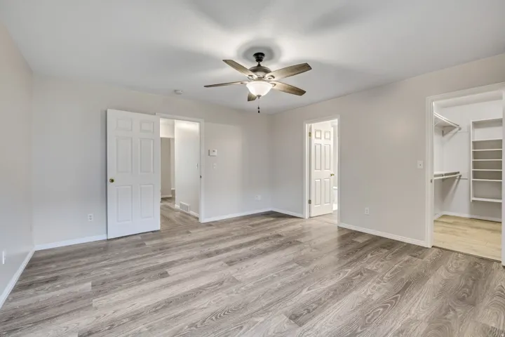 Unfurnished bedroom featuring a walk in closet, light wood-type flooring, and ceiling fan