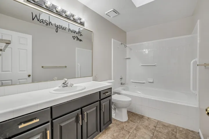 Full bathroom with vanity, bathtub / shower combination, and a skylight