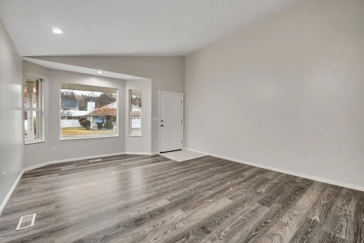 Empty room featuring lofted ceiling, dark wood-type flooring, and recessed lighting