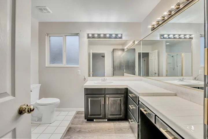 Bathroom with double vanity, light tile patterned floors, and a shower stall