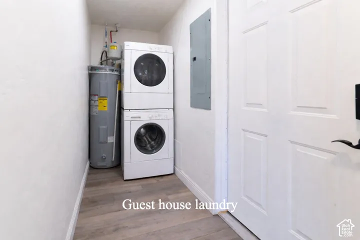 Laundry area featuring stacked washer / dryer, electric water heater, dark wood-style floors, and electric panel