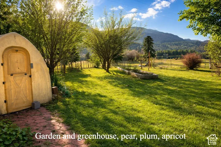 Garden area with fruit trees, greenhouse, and vegetable garden.