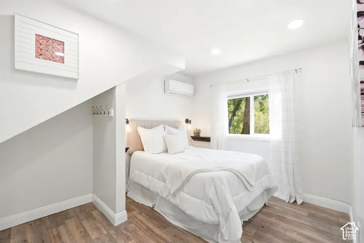 Bedroom featuring wood-finish flooring, recessed lighting, and a window with natural light