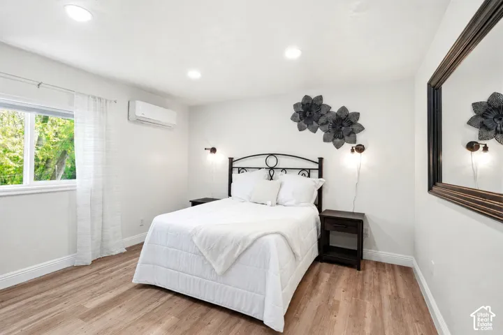 Bedroom featuring wood-finish flooring, recessed lighting, and a window with white trim
