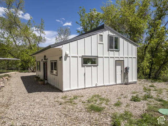 Modern farmhouse-style structure featuring white board-and-batten siding, a dark pitched roof, varied window sizes with contrasting trim, and exterior lighting fixtures