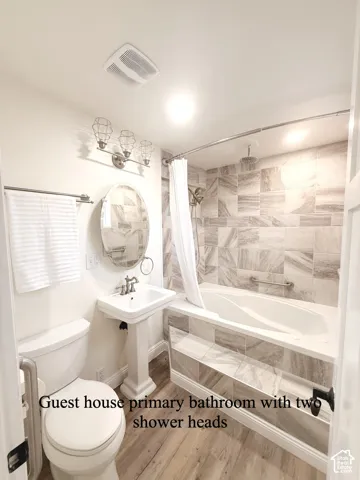 Full bathroom with light wood-type flooring and a combined bath / shower with rainfall shower
