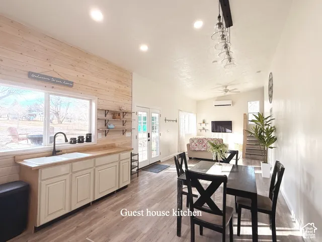 Dining space featuring french doors, wooden walls, light wood-type flooring, ceiling fan, and recessed lighting