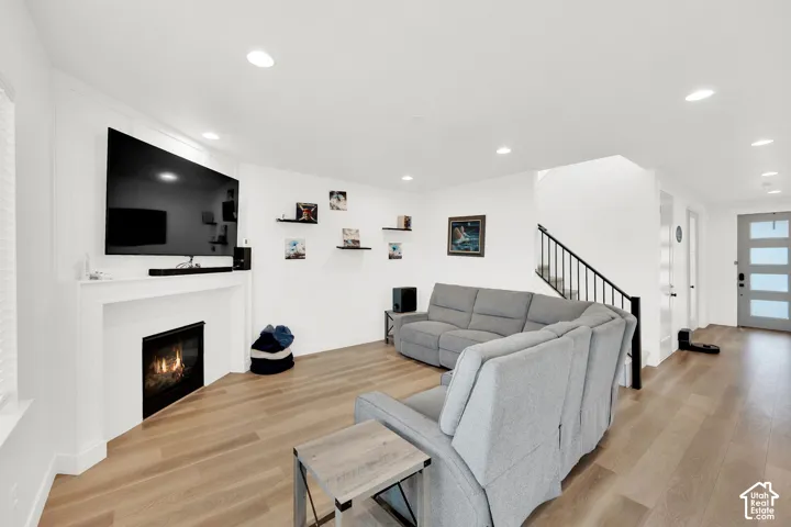 Living room with light wood-style floors, recessed lighting, and a glass covered fireplace