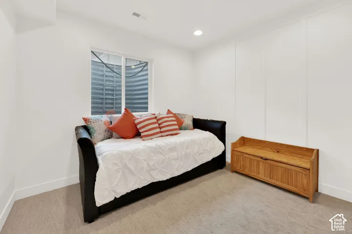 Carpeted bedroom featuring recessed lighting and a decorative wall