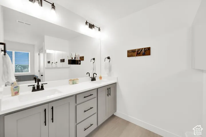 Full bathroom with double vanity and light tile patterned floors