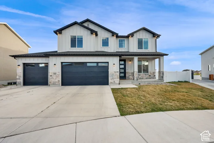 Modern inspired farmhouse featuring board and batten siding, covered porch, concrete driveway, a garage, and stone siding