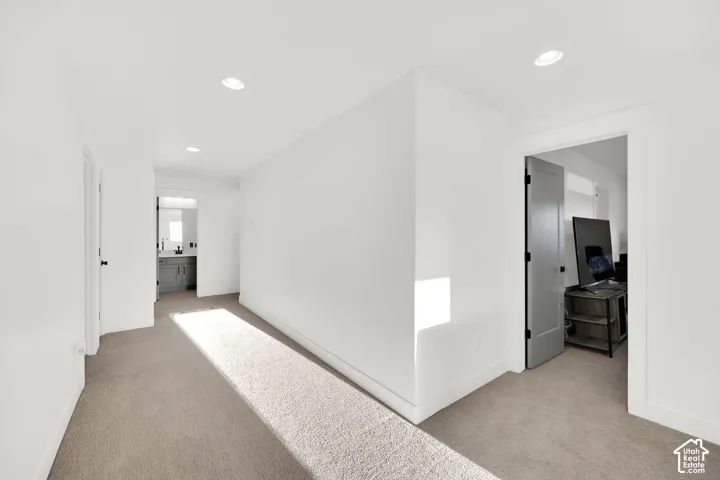 Hall with recessed lighting and light colored carpet