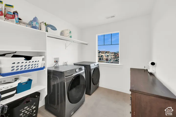 Laundry area with washing machine and clothes dryer and light tile patterned floors